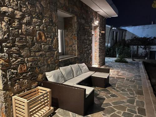 a patio with a couch and a stone wall at The Small Mountain house in Séta