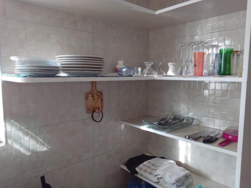 a kitchen with white tiled walls and shelves with dishes at Casa Carapibus Ale in Conde