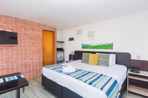 1 dormitorio con 1 cama grande y pared de ladrillo en Hotel Guatatur en Guatapé