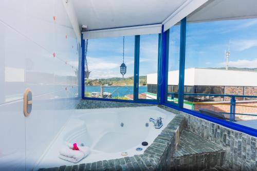a bath tub in a room with a large window at Hotel Guatatur in Guatapé
