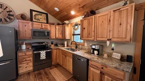 a kitchen with wooden cabinets and a black appliances at Twinn Peaks Beautiful Modern Mountain Cabin Retreat-Cozy-Secluded-WiFi-Pets in Murphy