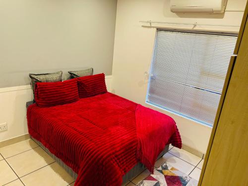 un letto rosso con cuscini rossi in una camera da letto di Comfort a Kathu