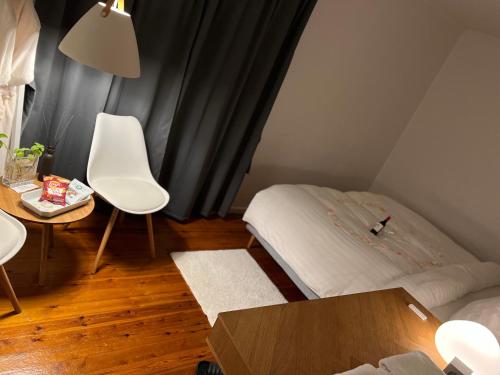 Habitación pequeña con cama, mesa y sillas en Unik BnB midt i byen - mad event og bilopladning, en Herning