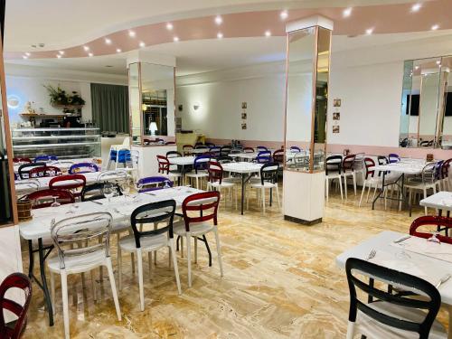 una sala da pranzo con tavoli e sedie bianchi di hotel iris a Rimini