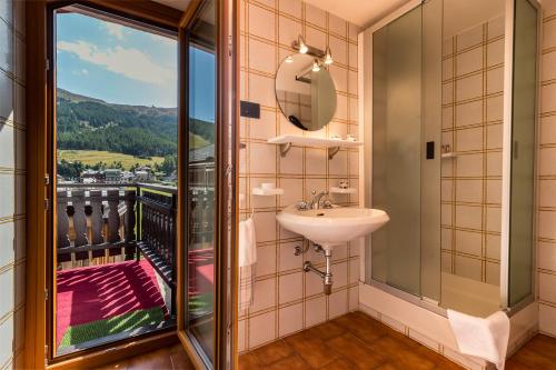 a bathroom with a sink and a balcony with a view at Bait da Menego in Livigno