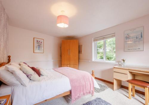 a bedroom with a bed and a desk and a window at Granary Cottage in Swimbridge
