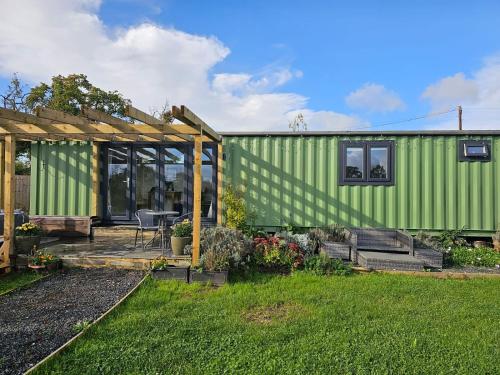 a green house with a table and a patio at Sweet Pea Cabin in Badsey