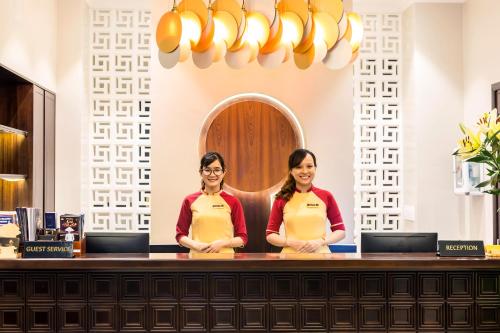two women in aprons standing in front of a counter at Laluna Hoi An Riverside Hotel & Spa in Hoi An