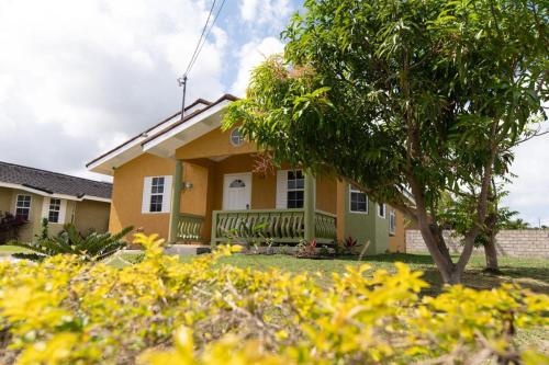 a yellow house with a tree in front of it at Stafford Oasis in Discovery Bay
