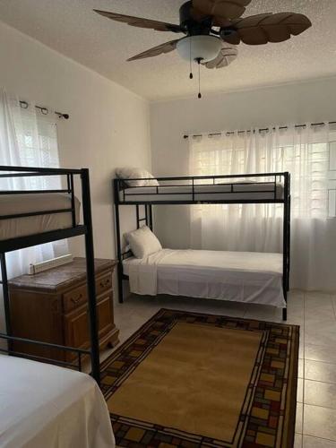 een slaapkamer met 2 stapelbedden en een plafondventilator bij Villa Maat 5 minutes to Winnifred Beach in Port Antonio