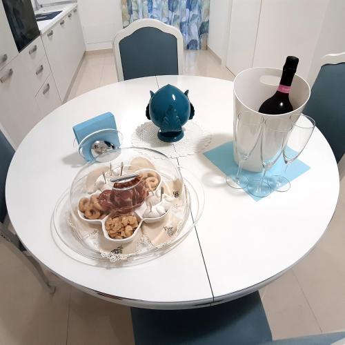 a white table with a plate of food and a bottle of wine at Balcone in Valle d'Itria in Martina Franca