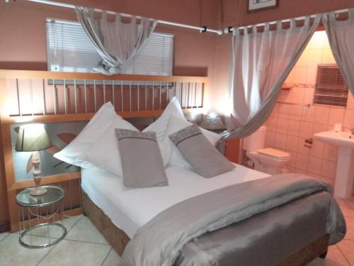 a bedroom with a bed with white sheets and pillows at Nthateng Bed and Breakfast in Soweto