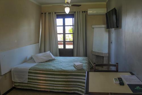 a hotel room with a bed and a window at Serramar Apart Hotel in Capão da Canoa
