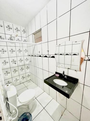 a white bathroom with a toilet and a sink at Casa de serra -3 quartos in Ubajara