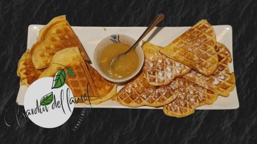 a white plate with waffles and a bowl of dipping sauce at El Jardín del Laurel in Candelario