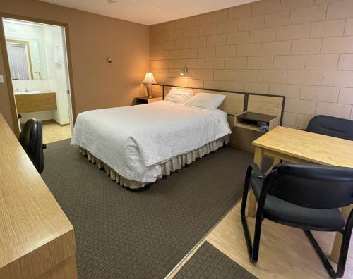 a hotel room with a bed and a table and chairs at Rest Easy Motel in Three Hills