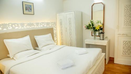 a bedroom with a white bed and a vase of flowers at CherryStay Holiday Resort -Candolim Beach in Candolim