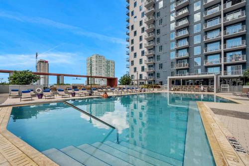 a large swimming pool with chairs and a building at Luxury 1 BR with DEN Downtown Tampa Apt - City Views, Rooftop Pool, Workspace in Tampa