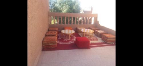 un balcón con almohadas, mesas y una valla en PALM'SKOURA en Skoura