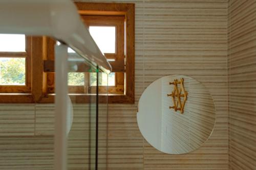 a round mirror on a wall in a bathroom at Blue House Vale do Capão in Palmeiras