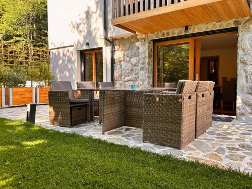 a patio with wicker chairs and a table in front of a house at The Vila Bled Premium Luxury Retreat in Bled