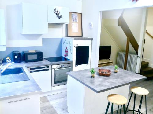 une cuisine avec des armoires blanches et un comptoir avec des tabourets dans l'établissement Family Home, à Sens