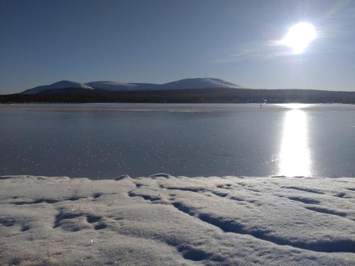 a body of water with the sun shining on the snow at Yllästölli 2 A, Äkäslompolo in Kolari