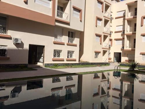 eine Reflexion eines Gebäudes in einem Wasserpool in der Unterkunft Appartement Cosy Residence avec 2 Piscines in Marrakesch
