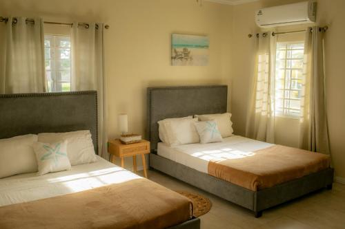 two beds in a room with two windows at The Nest Villa, A Dream Escape for the entire family in Golden Grove