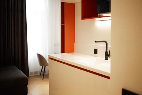eine Küche mit einem weißen Waschbecken und einer orangefarbenen Wand in der Unterkunft BARBAR APART HOTEL in Gjumri