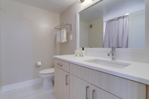 a bathroom with a sink and a toilet and a mirror at Elegance in Crystal City - Amazing Condo with gym in Arlington