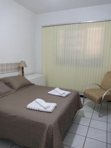 a bedroom with a bed and a chair and a window at Apartamento 1 in Florianópolis