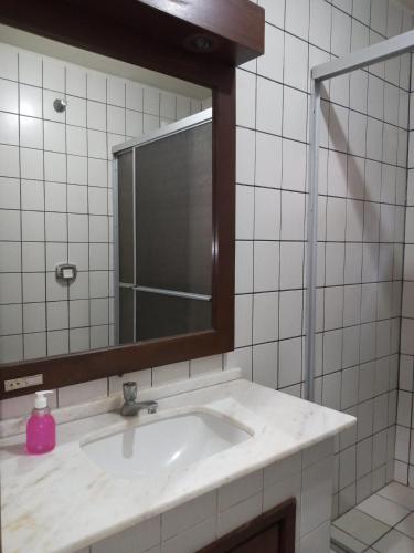 a bathroom sink with a mirror and a pink soap bottle at Apartamento 1 in Florianópolis
