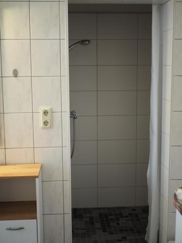 um chuveiro na casa de banho com azulejos brancos em Jarmen Ferienwohnung em Jarmen