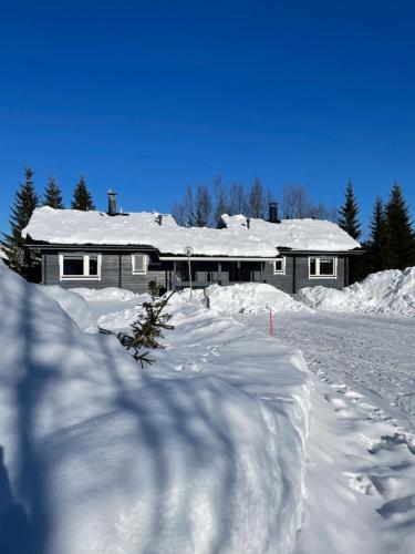 a house covered in snow with a pile of snow at Yllästölli 2 D, Äkäslompolo in Kolari