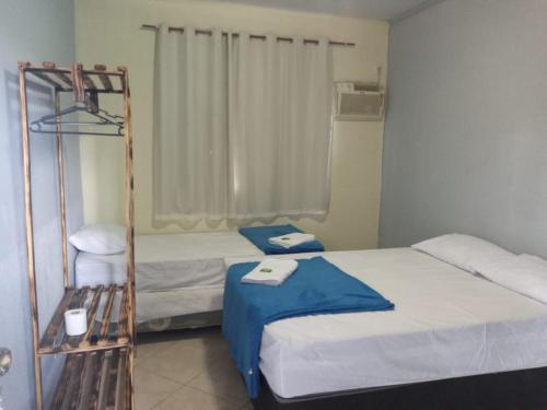 um pequeno quarto com 2 camas e uma cadeira em HOTEL EUROPA FAMILIAr em Alto Paraíso de Goiás