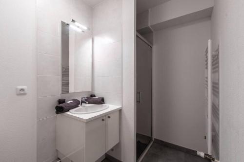 une salle de bain blanche avec un lavabo et un miroir dans l'établissement Fleur de sel * Terrasse* chambre * parking, au Grau-du-Roi