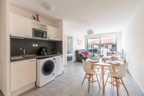 Il comprend une cuisine et un salon avec une table et un lave-linge. dans l'établissement Fleur de sel * Terrasse* chambre * parking, au Grau-du-Roi