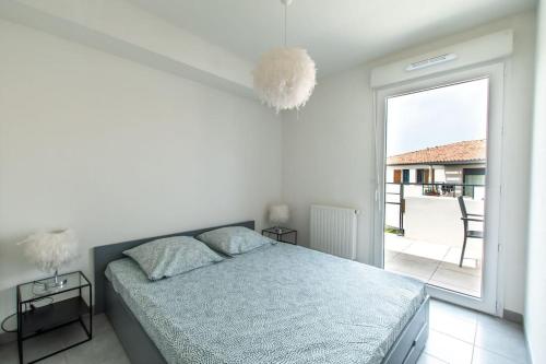 une chambre blanche avec un lit et une grande fenêtre dans l'établissement Fleur de sel * Terrasse* chambre * parking, au Grau-du-Roi