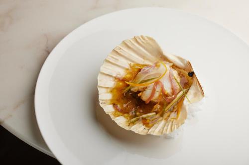 a oyster on a white plate on a table at 5 Terres Hotel & Spa - MGallery Collection in Barr