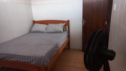 a small bedroom with a bed and a chair at Kitnet em Aracaju para 3 pessoas in Aracaju