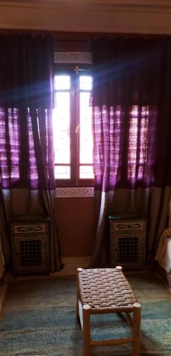 a room with purple curtains and a bench in front of a window at maison d'hôtes Le petit jardin Marrakech in Marrakech