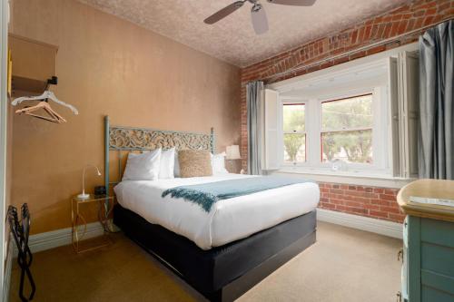 a bedroom with a bed and a brick wall at Grand Highland Hotel in Prescott