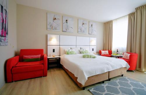 a bedroom with a large bed and a red chair at Apartment prywatny w Hotelu Diwa w strefie kurortowej z klimatyzacja i Parkingiem wcentrum Kolobrzegu in Kołobrzeg