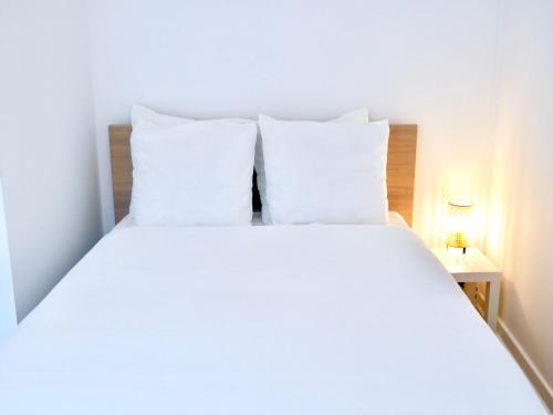 a white bed with white pillows in a bedroom at Travel Rio Logement en Colocation in Sens