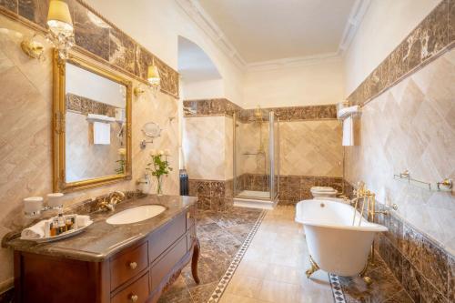 y baño grande con bañera, lavamanos y bañera. en Galicia Nueva, castle hotel en Lučenec