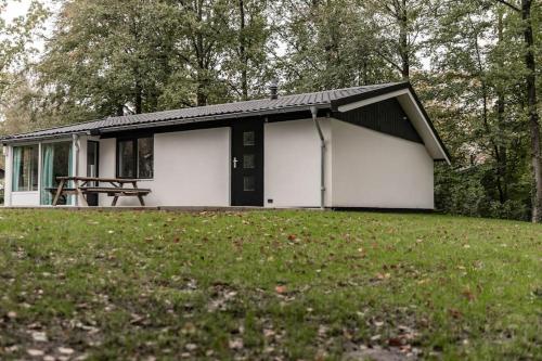 a small white house with a picnic table in a field at Fenna's Holiday Home in Exloo