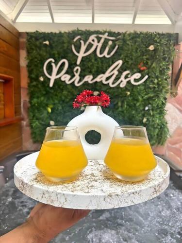 a person holding a tray with two glasses and a vase at P'ti Paradise in Le Gosier