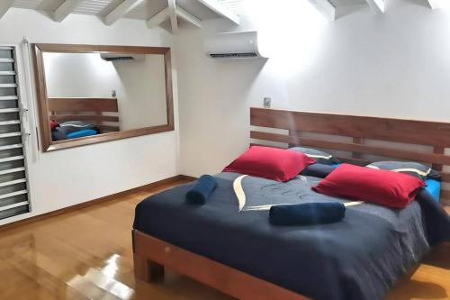 1 dormitorio con 1 cama grande con almohadas rojas y espejo en P'ti Paradise, en Le Gosier