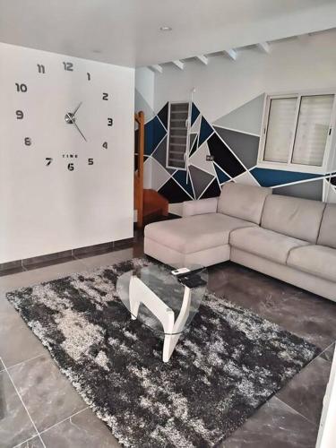 a living room with a couch and a clock on the wall at P'ti Paradise in Le Gosier